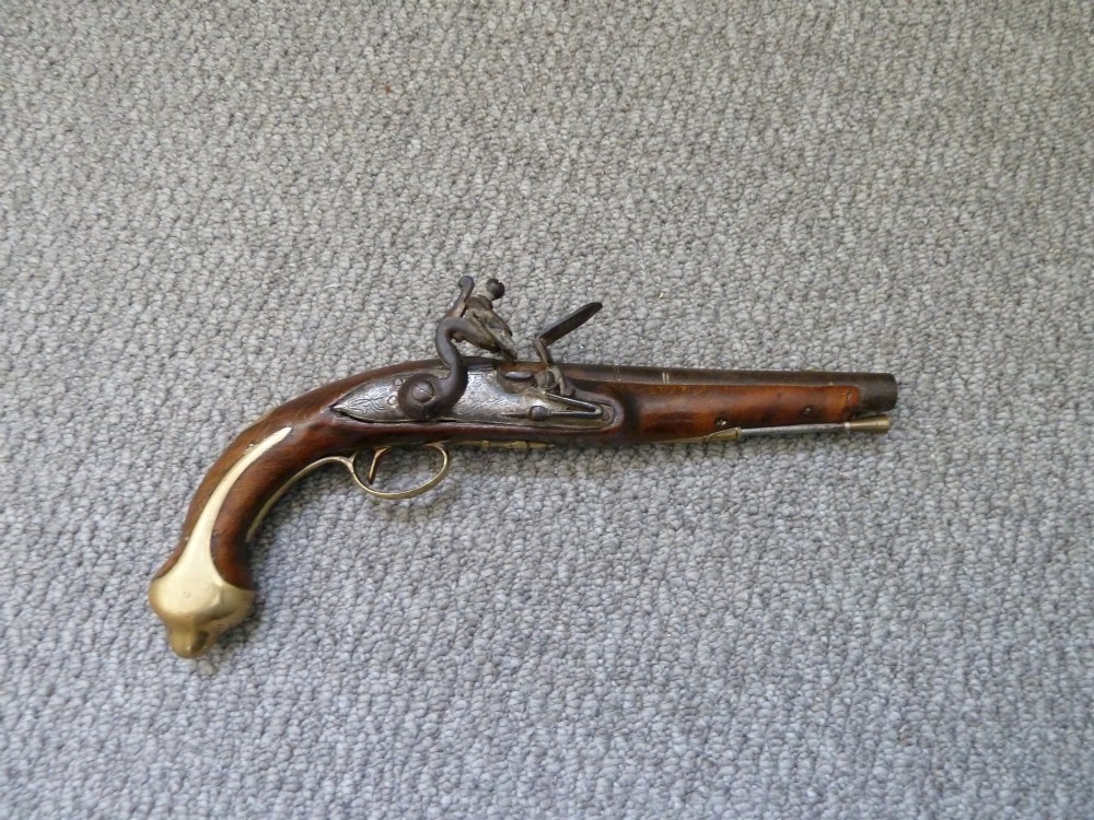 An 18th-century flintlock pistol featuring a dark walnut stock, engraved steel lock mechanism, and polished brass fittings.