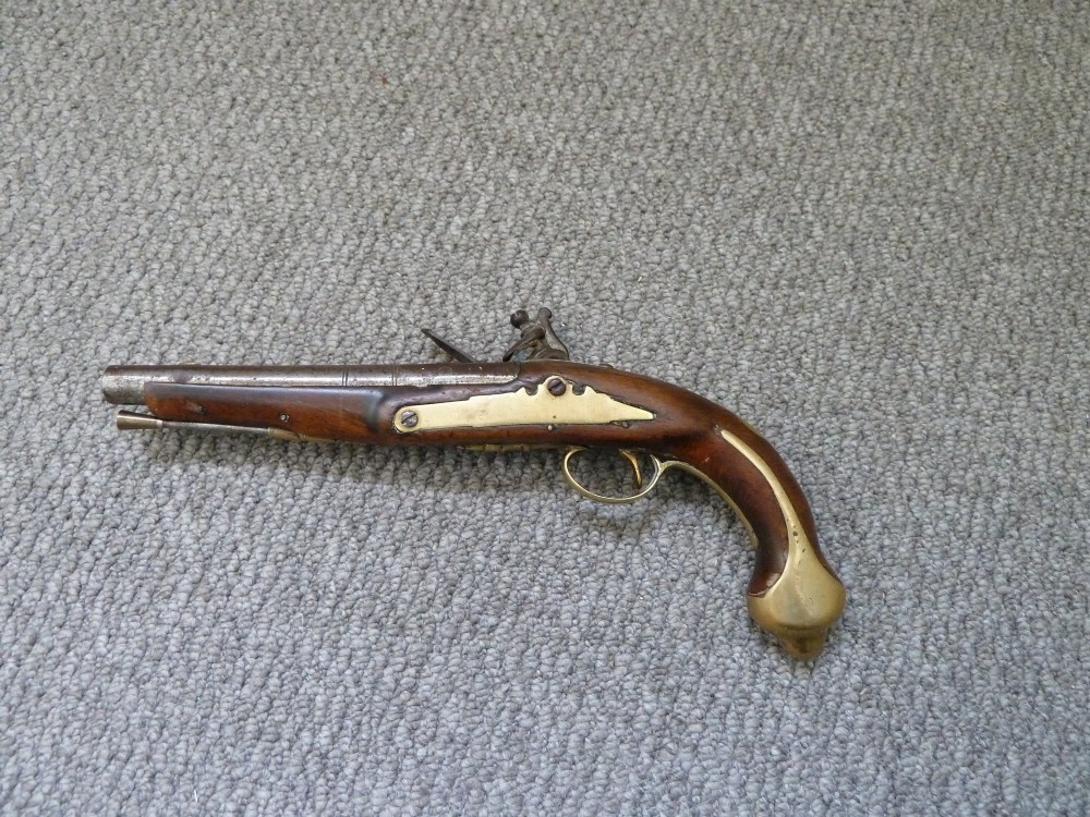 An 18th-century flintlock pistol featuring a dark walnut stock, engraved steel lock mechanism, and polished brass fittings. View II