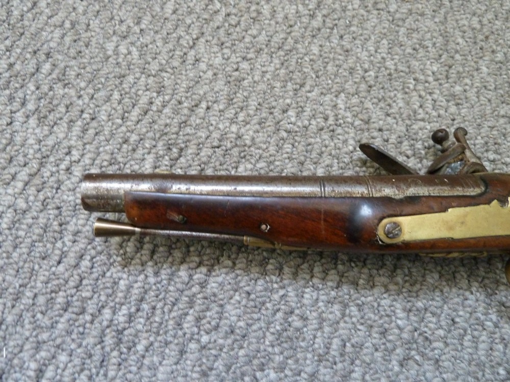 An 18th-century flintlock pistol featuring a dark walnut stock, engraved steel lock mechanism, and polished brass fittings. View VIII