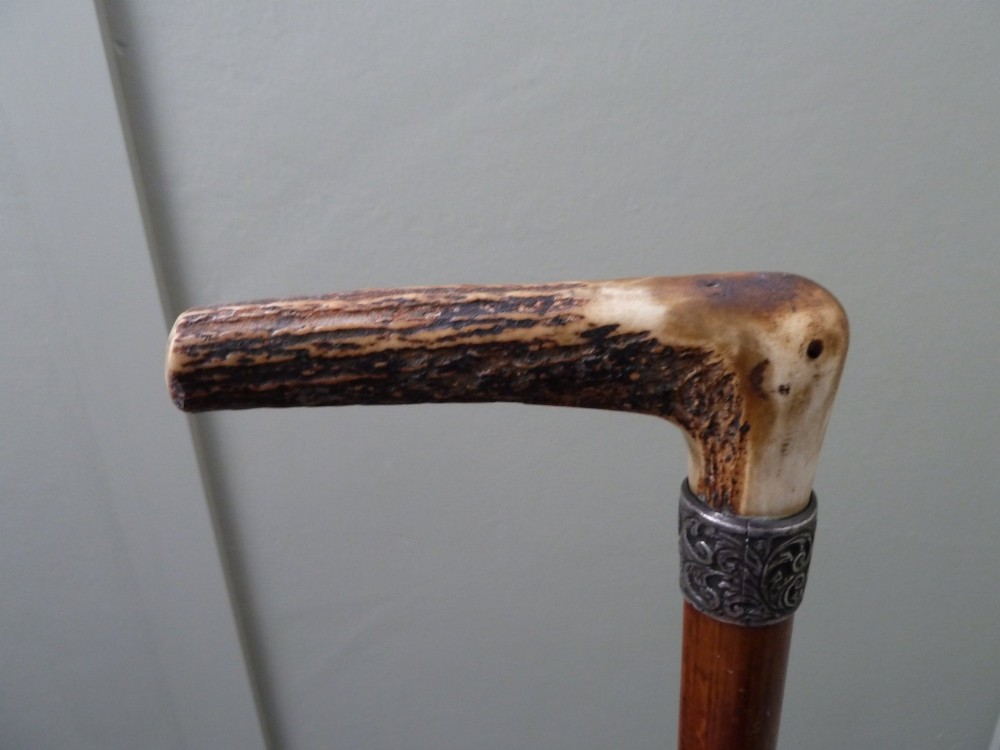 A Victorian sword stick displayed unsheathed in two parts, showcasing a stag horn handle, decorative metal ferrule, dark wooden scabbard, and a narrow steel blade. View X