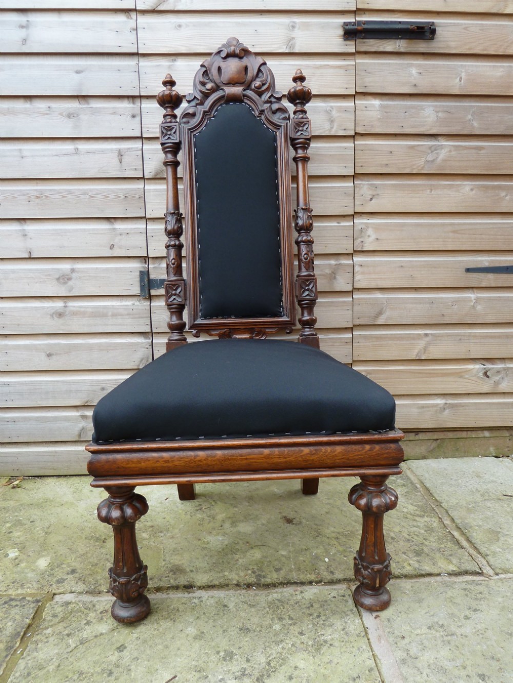 A set of four Victorian Gothic style carved oak high-back chairs featuring black upholstered seats and backrests with ornate cresting and turned legs. View V