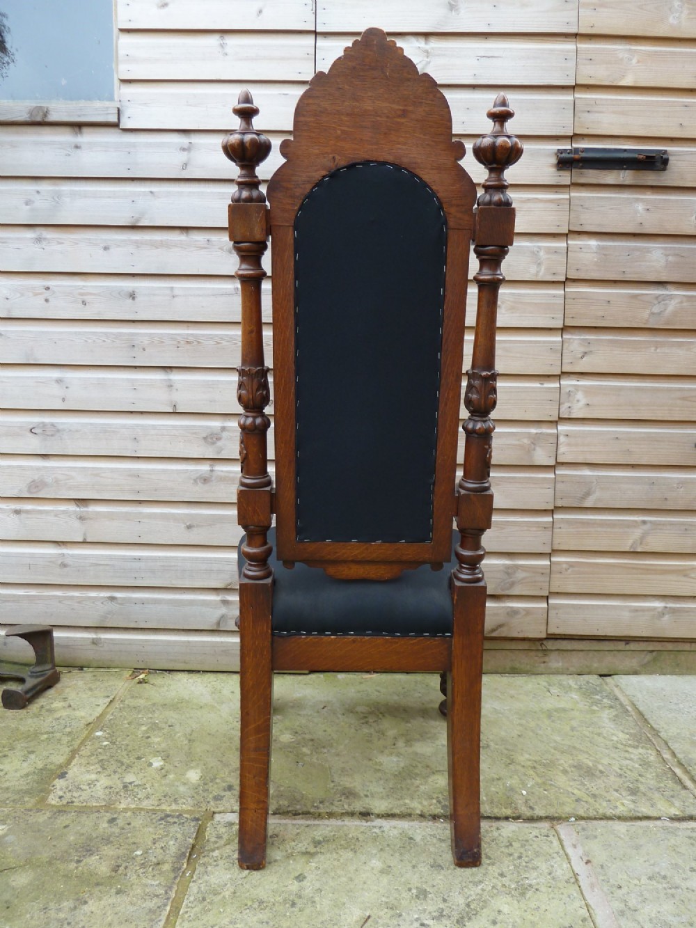 A set of four Victorian Gothic style carved oak high-back chairs featuring black upholstered seats and backrests with ornate cresting and turned legs. View VIII