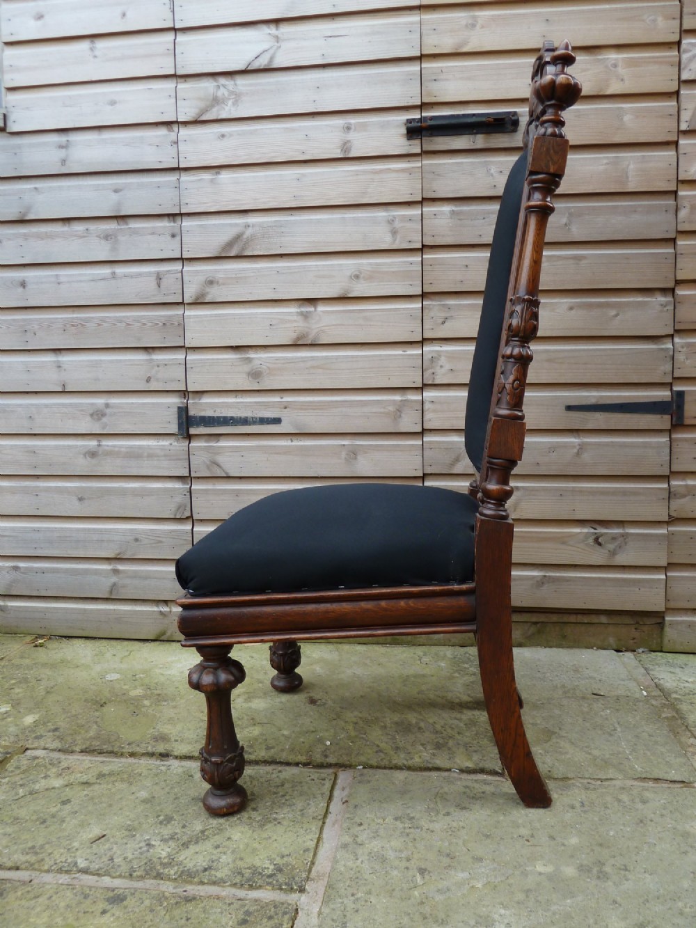 A set of four Victorian Gothic style carved oak high-back chairs featuring black upholstered seats and backrests with ornate cresting and turned legs. View IX