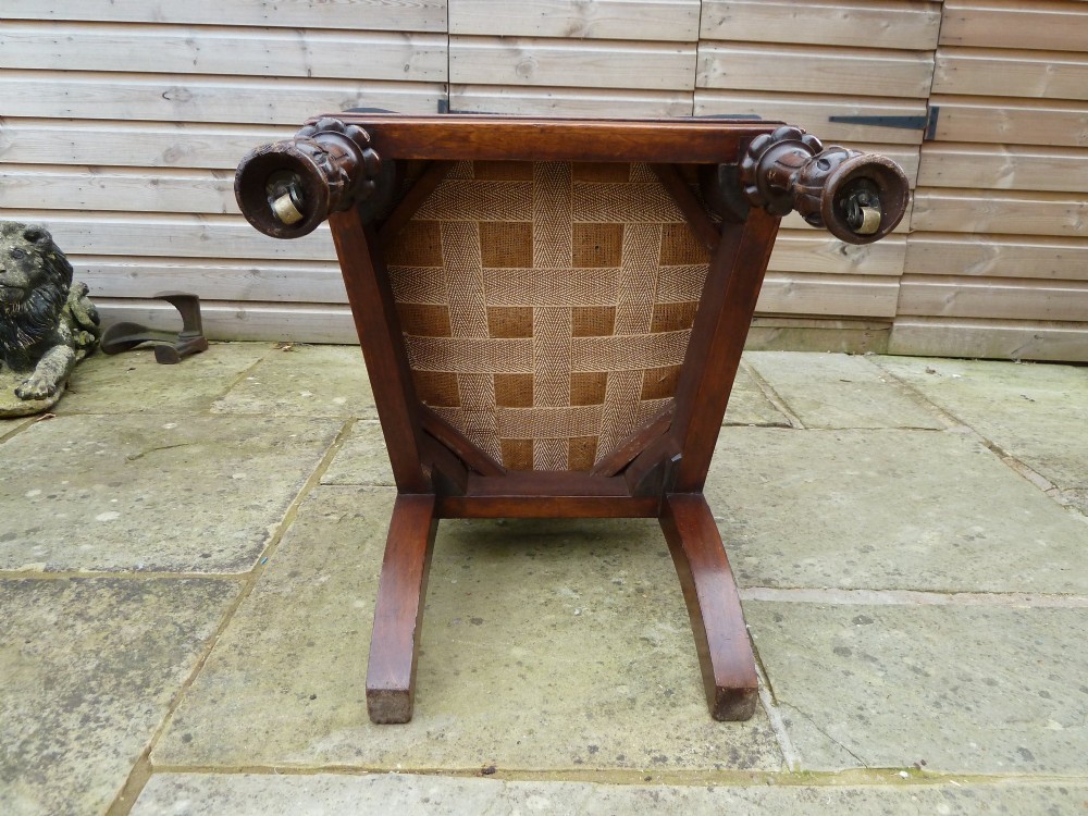 A set of four Victorian Gothic style carved oak high-back chairs featuring black upholstered seats and backrests with ornate cresting and turned legs. View X