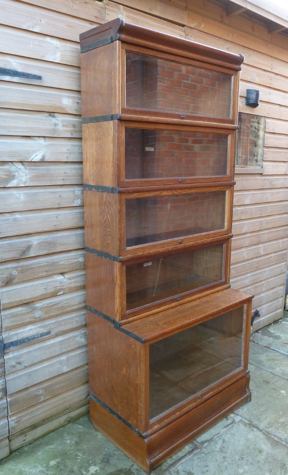 A tall five-tier golden oak Globe Wernicke sectional bookcase featuring glass lift-up doors and a deeper base unit. View IV