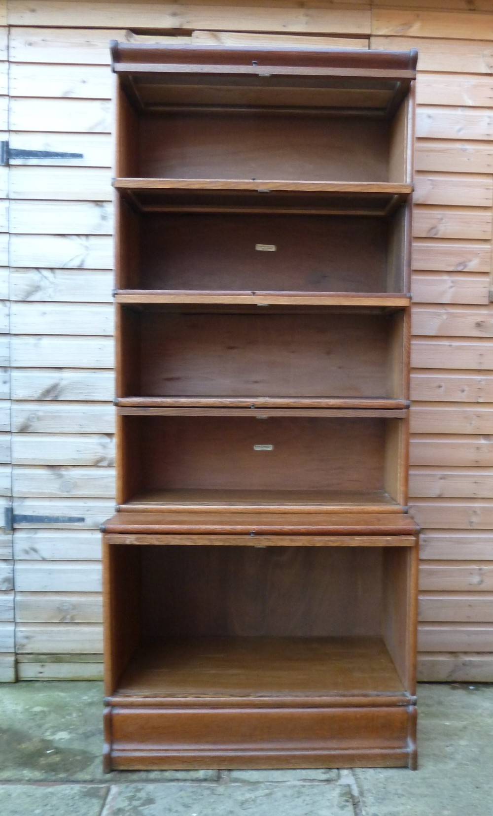 A tall five-tier golden oak Globe Wernicke sectional bookcase featuring glass lift-up doors and a deeper base unit. View VII