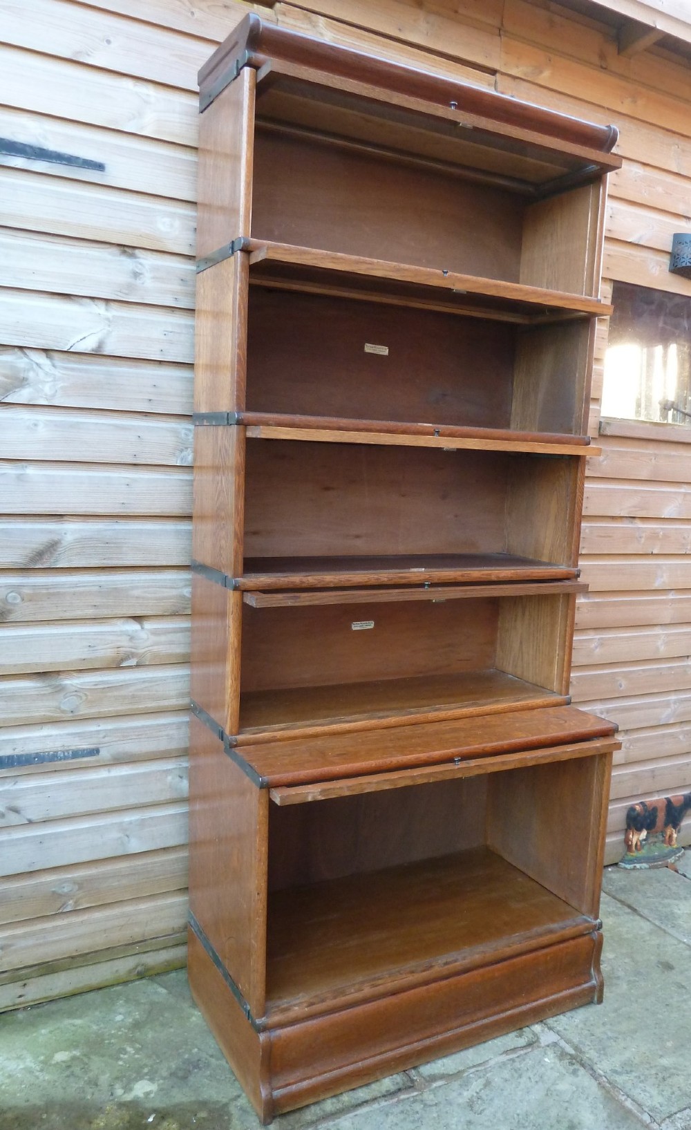 A tall five-tier golden oak Globe Wernicke sectional bookcase featuring glass lift-up doors and a deeper base unit. View IX