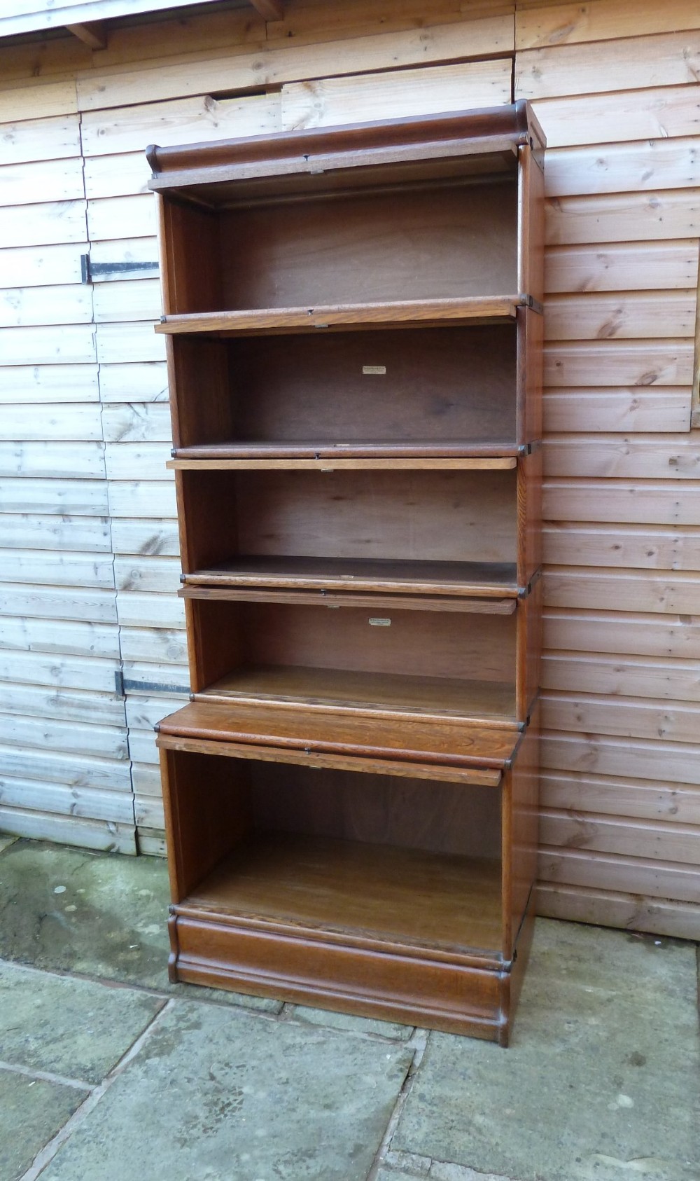 A tall five-tier golden oak Globe Wernicke sectional bookcase featuring glass lift-up doors and a deeper base unit. View XI