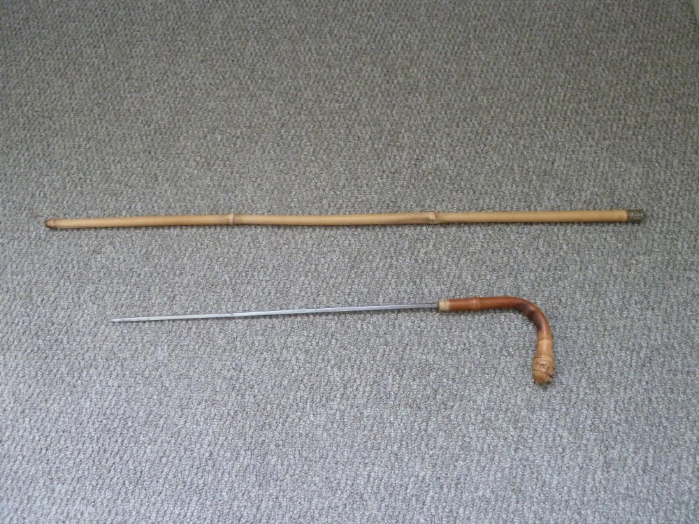 A Victorian bamboo walking stick displayed unsheathed alongside its concealed long steel blade attached to a curved bamboo crook handle.