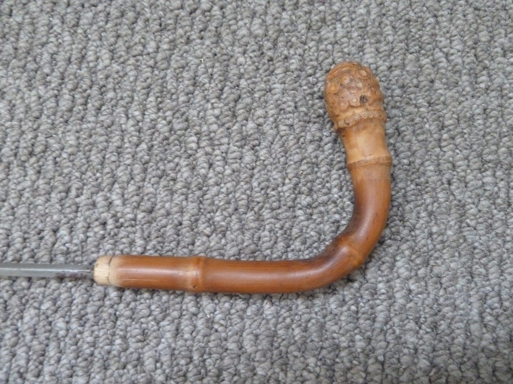 A Victorian bamboo walking stick displayed unsheathed alongside its concealed long steel blade attached to a curved bamboo crook handle. View IV