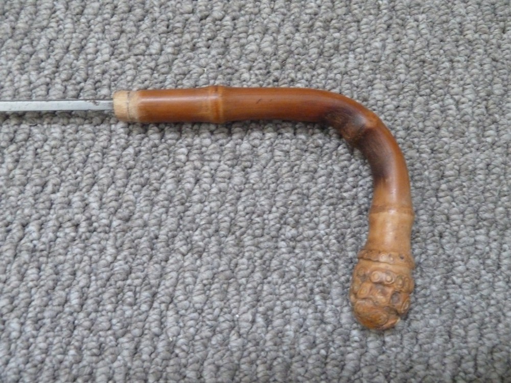 A Victorian bamboo walking stick displayed unsheathed alongside its concealed long steel blade attached to a curved bamboo crook handle. View V