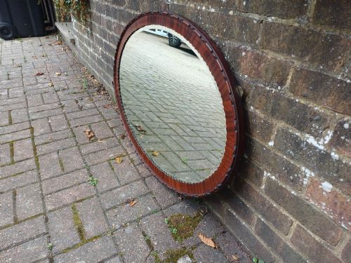 fig 2. A large horizontal oval wall mirror featuring a carved mahogany wooden frame and a bevelled glass edge.