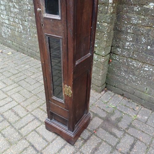 fig 5. A tall, narrow Victorian dark oak gun cupboard featuring two glass panels set into a single front door with decorative brass hinges.