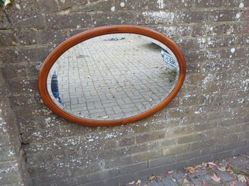 fig 1. An oval mahogany framed wall mirror featuring a bevelled glass edge and subtle fine string inlay detail around the perimeter.