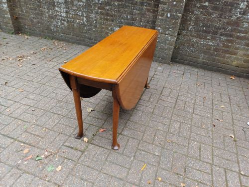 fig 1. An antique mahogany drop-leaf dining table with one hinged leaf raised, standing on tapered legs with pad feet.