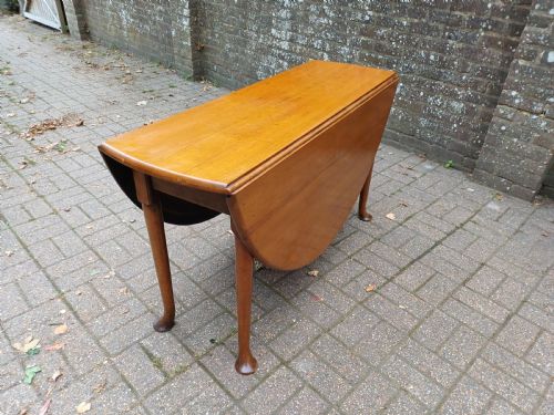 fig 7. An antique mahogany drop-leaf dining table with one hinged leaf raised, standing on tapered legs with pad feet.