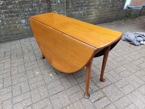 fig 8. An antique mahogany drop-leaf dining table with one hinged leaf raised, standing on tapered legs with pad feet.