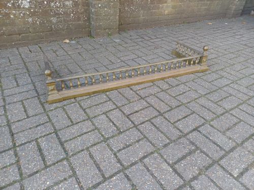 fig 1. An antique brass fireplace fender featuring a turned spindle balustrade, spherical corner finials, and a stepped plinth base.