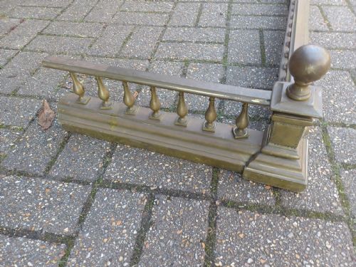 fig 4. An antique brass fireplace fender featuring a turned spindle balustrade, spherical corner finials, and a stepped plinth base.