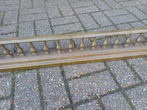 fig 5. An antique brass fireplace fender featuring a turned spindle balustrade, spherical corner finials, and a stepped plinth base.