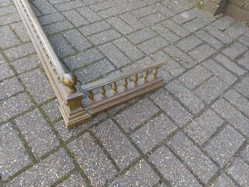 fig 8. An antique brass fireplace fender featuring a turned spindle balustrade, spherical corner finials, and a stepped plinth base.