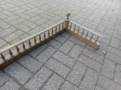 fig 9. An antique brass fireplace fender featuring a turned spindle balustrade, spherical corner finials, and a stepped plinth base.