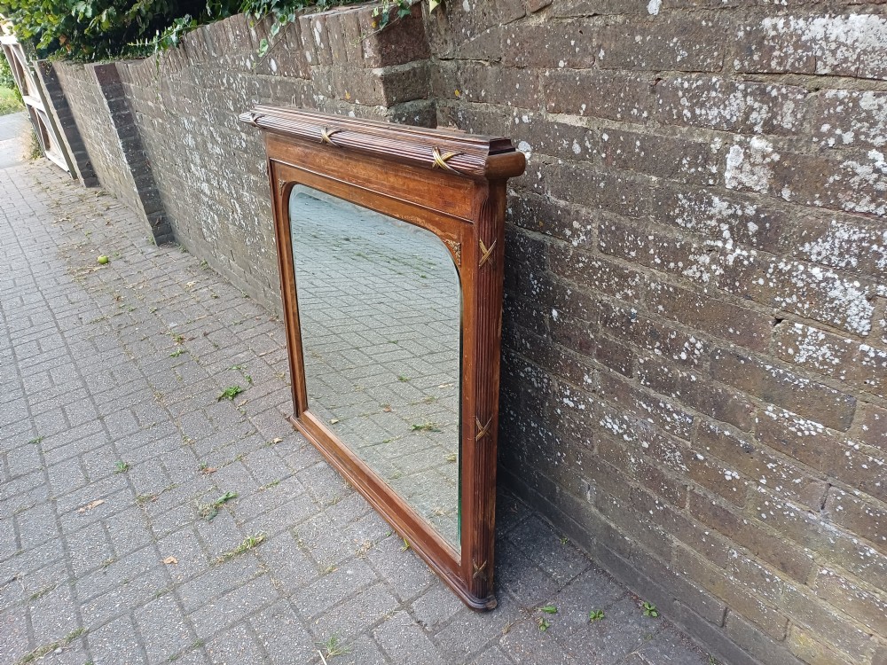 A large Edwardian wooden overmantel mirror featuring marquetry inlay, a reeded frame with gilded cross-ribbon details, and an arched upper glass line. View II