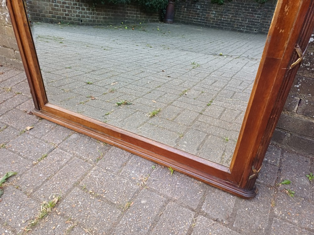 A large Edwardian wooden overmantel mirror featuring marquetry inlay, a reeded frame with gilded cross-ribbon details, and an arched upper glass line. View VI