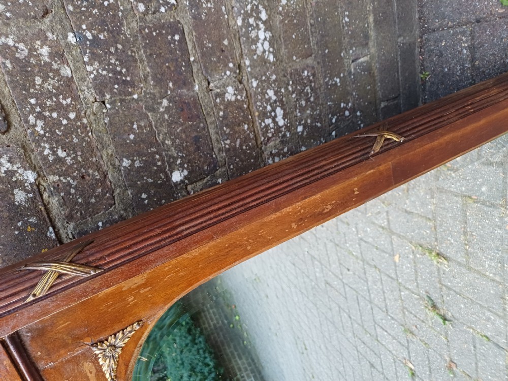 A large Edwardian wooden overmantel mirror featuring marquetry inlay, a reeded frame with gilded cross-ribbon details, and an arched upper glass line. View VIII