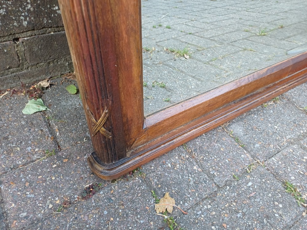 A large Edwardian wooden overmantel mirror featuring marquetry inlay, a reeded frame with gilded cross-ribbon details, and an arched upper glass line. View IX