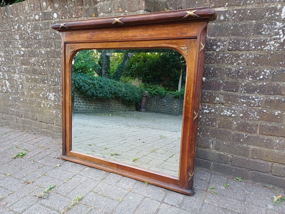 A large Edwardian wooden overmantel mirror featuring marquetry inlay, a reeded frame with gilded cross-ribbon details, and an arched upper glass line. View X