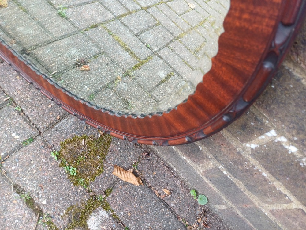 A large horizontal oval wall mirror featuring a carved mahogany wooden frame and a bevelled glass edge. View VI