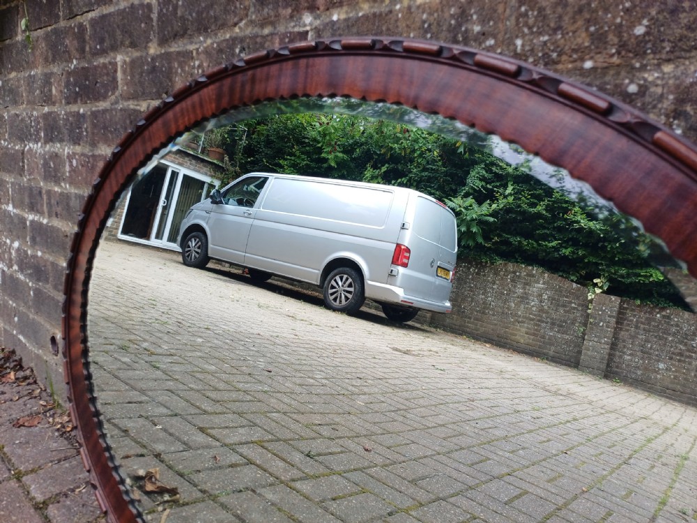 A large horizontal oval wall mirror featuring a carved mahogany wooden frame and a bevelled glass edge. View VIII