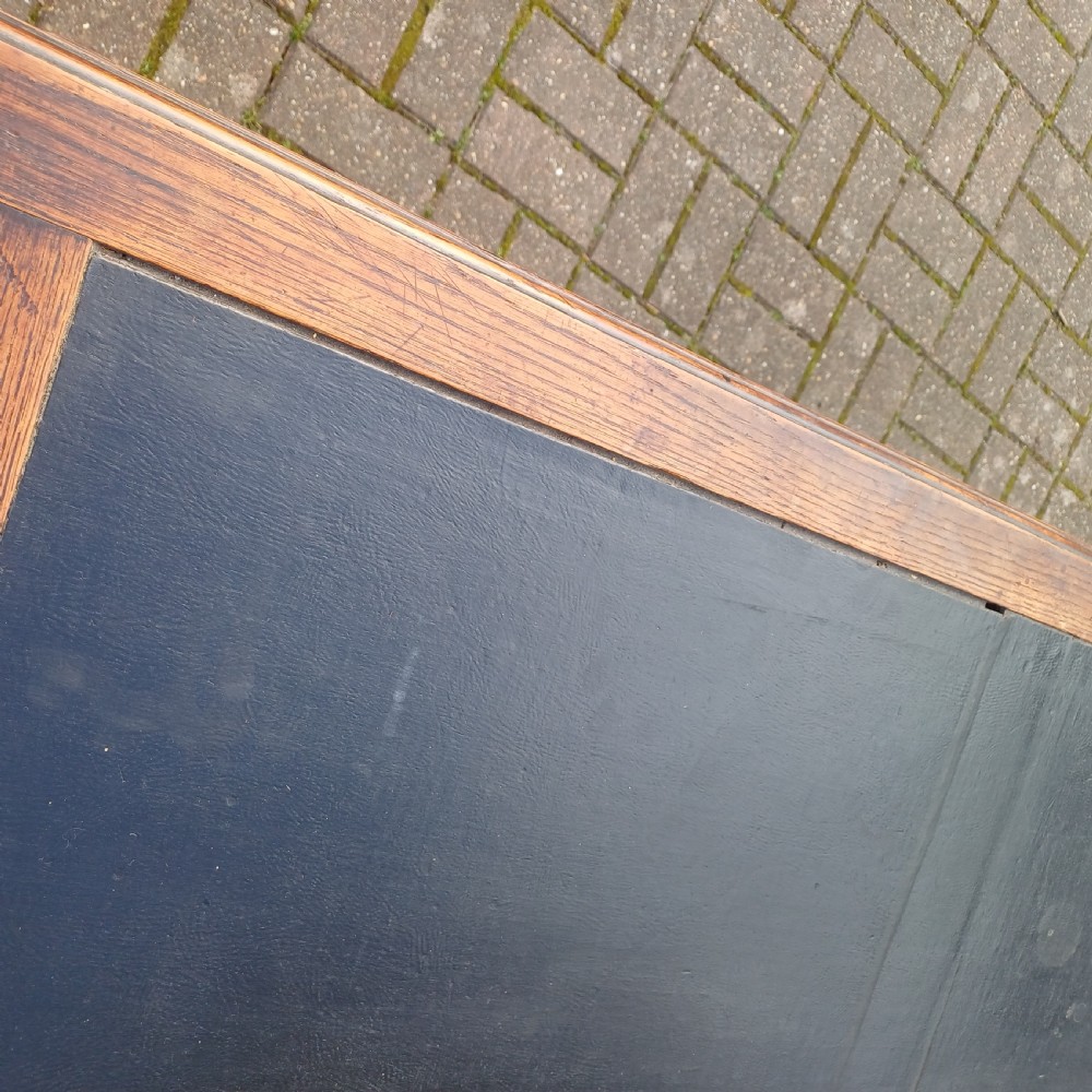 A vintage dark oak writing desk with five drawers, geometric bead moulding, turned legs, brass handles, and a black leather inset top. View IV