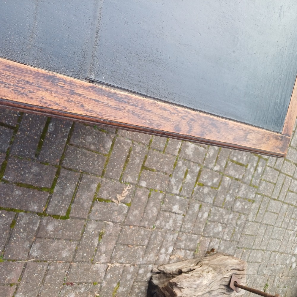 A vintage dark oak writing desk with five drawers, geometric bead moulding, turned legs, brass handles, and a black leather inset top. View V