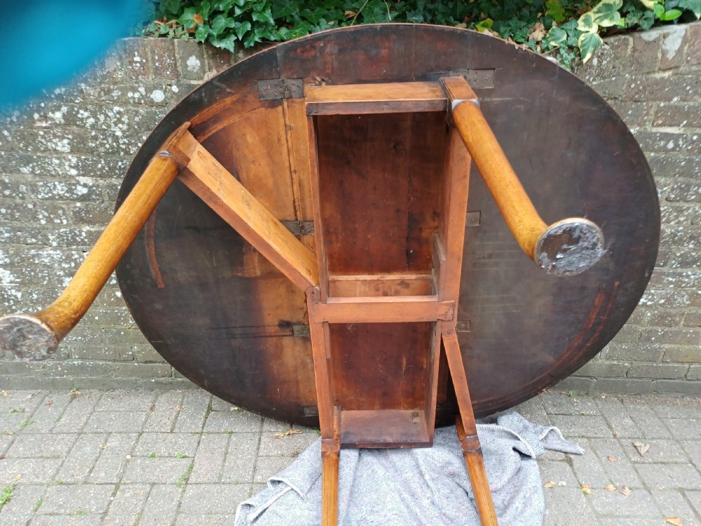 An antique mahogany drop-leaf dining table with one hinged leaf raised, standing on tapered legs with pad feet. View III
