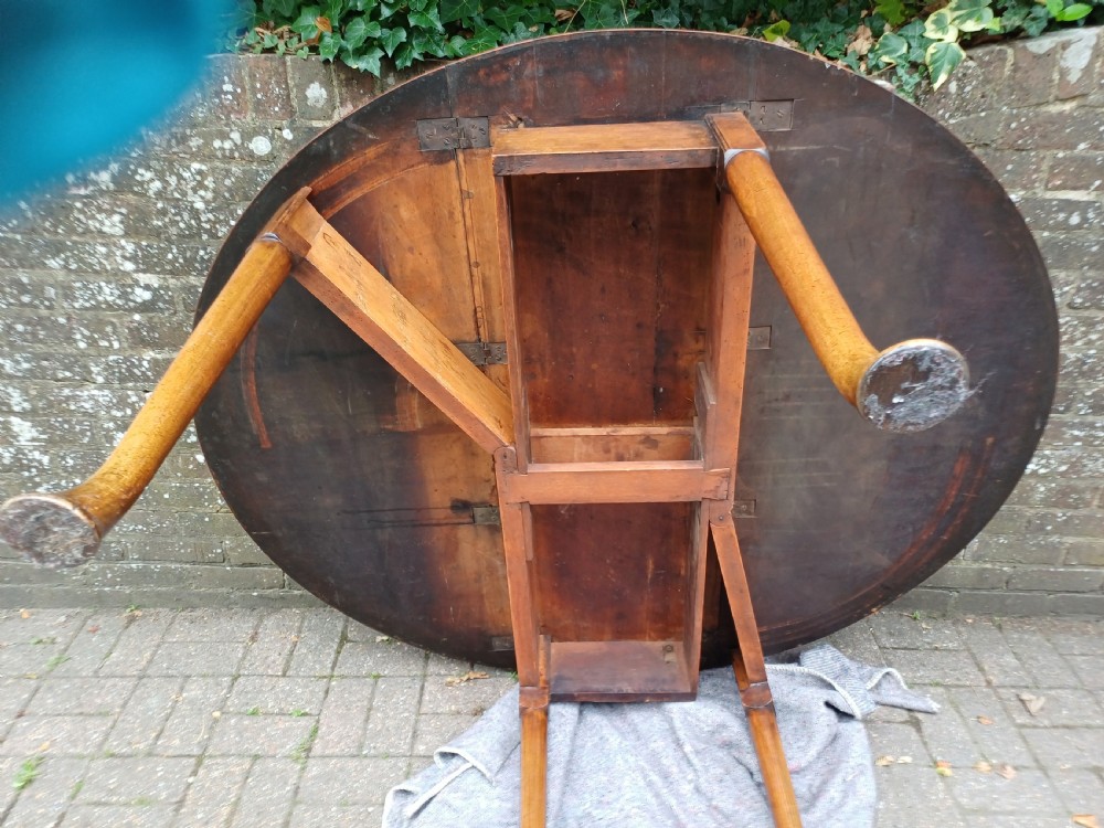 An antique mahogany drop-leaf dining table with one hinged leaf raised, standing on tapered legs with pad feet. View IV