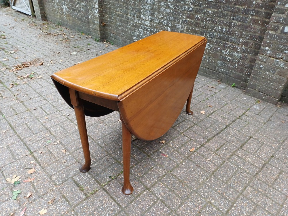 An antique mahogany drop-leaf dining table with one hinged leaf raised, standing on tapered legs with pad feet. View VIII