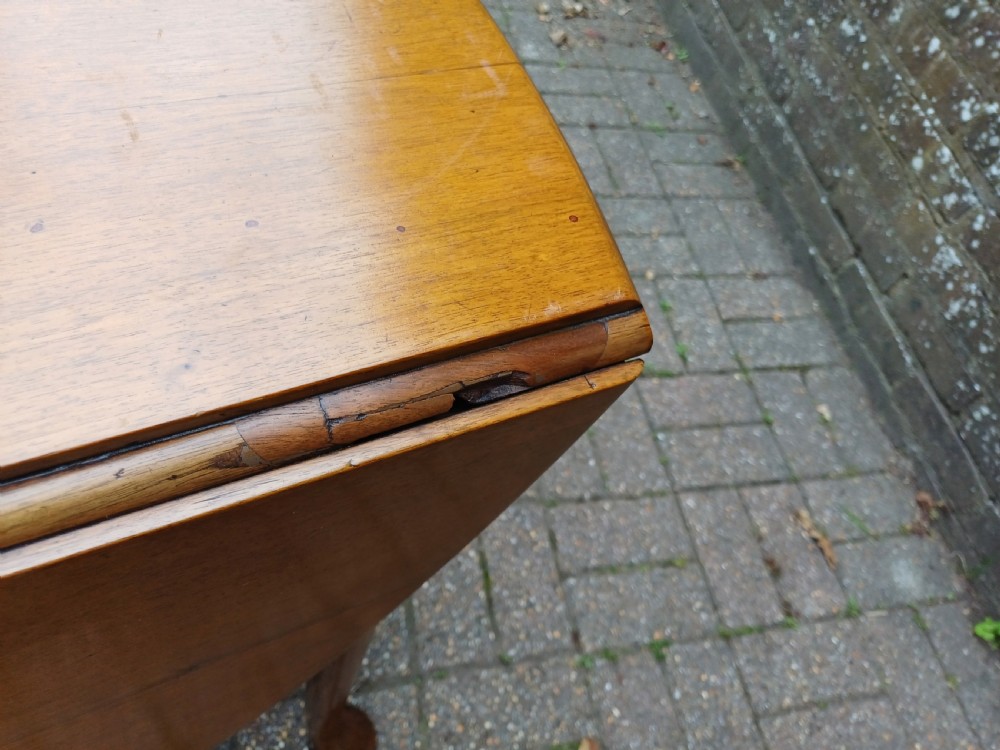 An antique mahogany drop-leaf dining table with one hinged leaf raised, standing on tapered legs with pad feet. View X