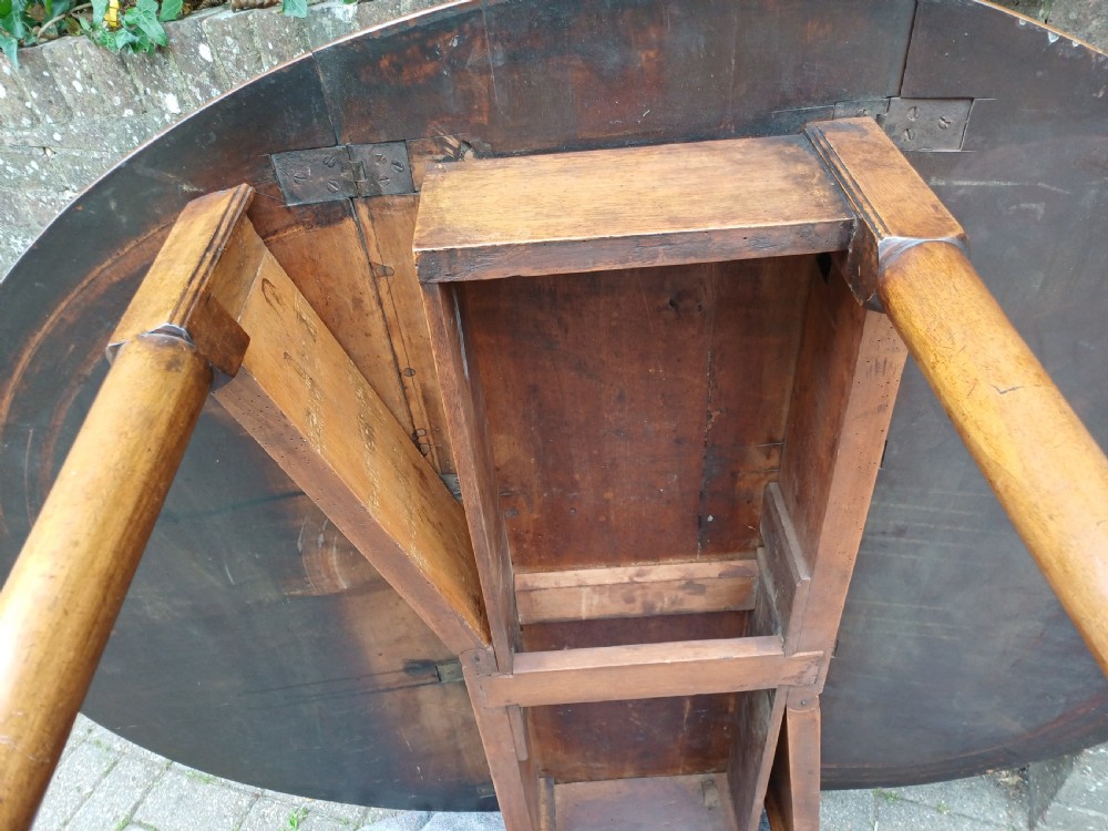 An antique mahogany drop-leaf dining table with one hinged leaf raised, standing on tapered legs with pad feet. View XIV