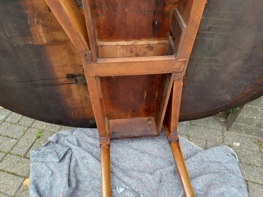 An antique mahogany drop-leaf dining table with one hinged leaf raised, standing on tapered legs with pad feet. View XV