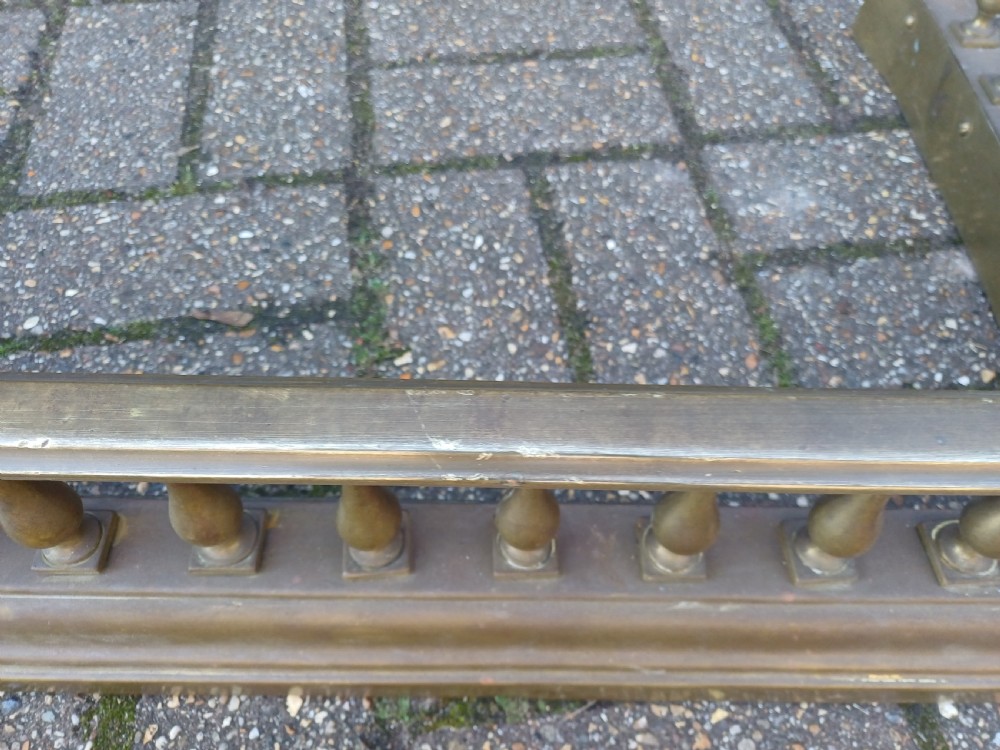 An antique brass fireplace fender featuring a turned spindle balustrade, spherical corner finials, and a stepped plinth base. View VIII