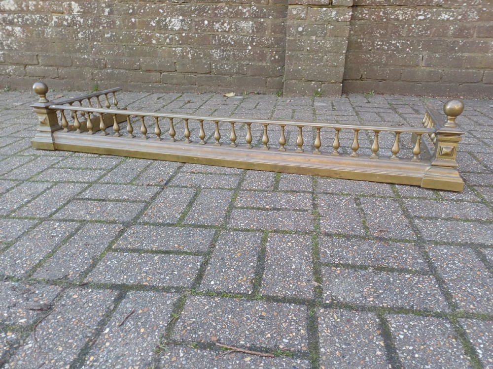 An antique brass fireplace fender featuring a turned spindle balustrade, spherical corner finials, and a stepped plinth base. View XIII