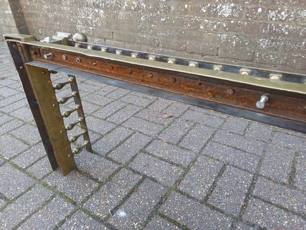 An antique brass fireplace fender featuring a turned spindle balustrade, spherical corner finials, and a stepped plinth base. View XV