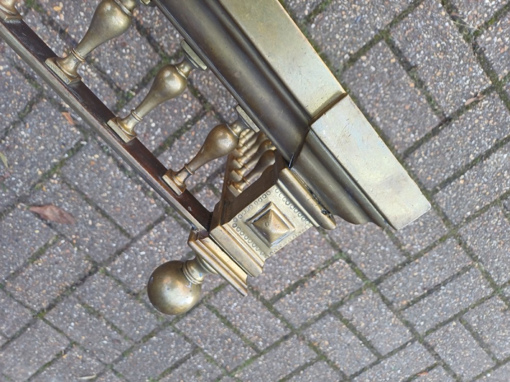 An antique brass fireplace fender featuring a turned spindle balustrade, spherical corner finials, and a stepped plinth base. View XVII