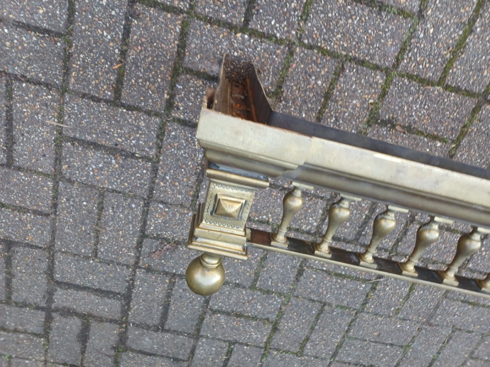 An antique brass fireplace fender featuring a turned spindle balustrade, spherical corner finials, and a stepped plinth base. View XVIII