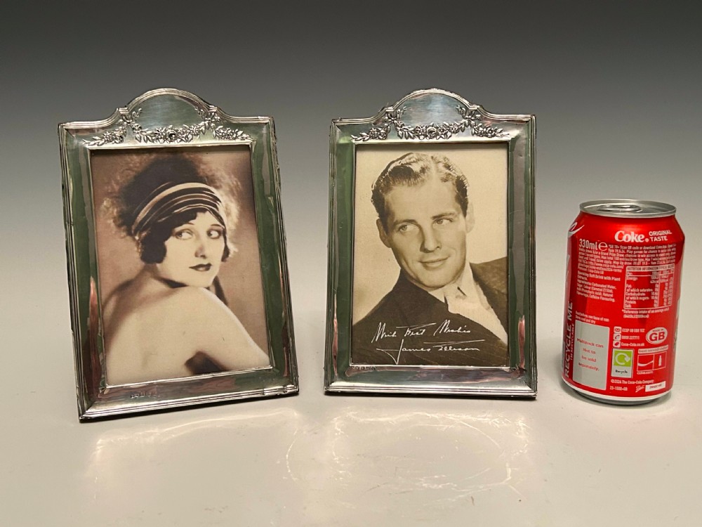 A pair of Edwardian hallmarked sterling silver picture frames with arched tops and floral relief moulding housing vintage black and white portrait photographs. View II