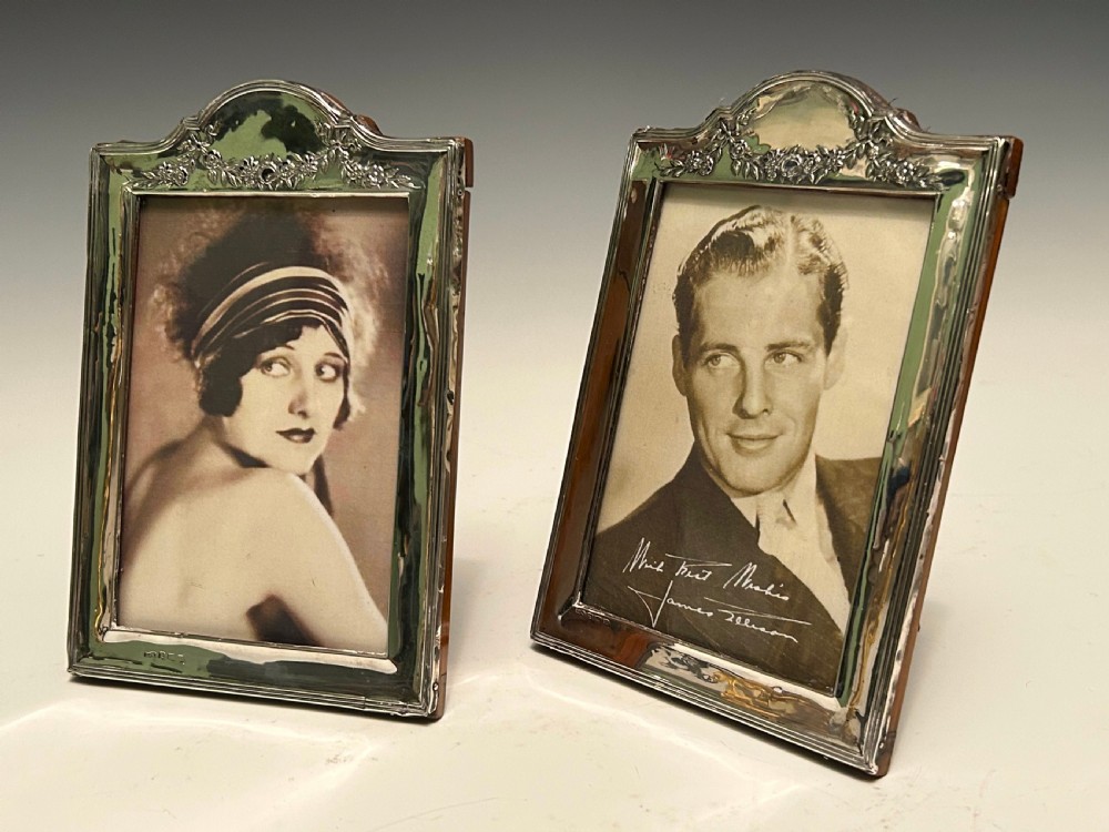 A pair of Edwardian hallmarked sterling silver picture frames with arched tops and floral relief moulding housing vintage black and white portrait photographs. View VI