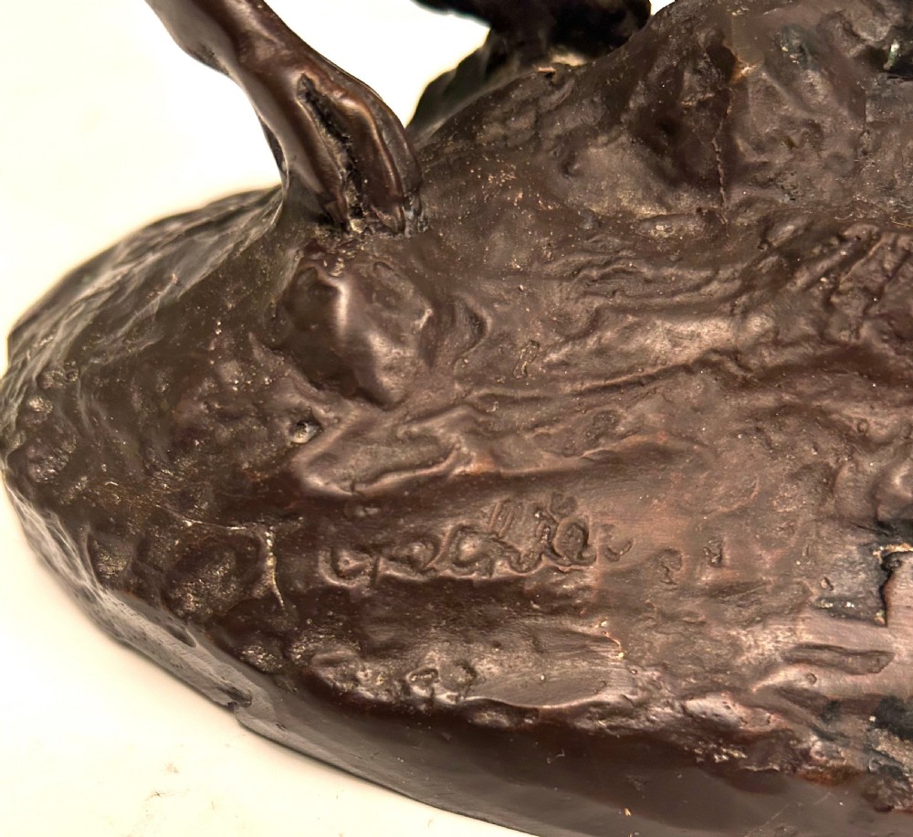 A dark brown patinated bronze sculpture depicting an alert standing greyhound on a textured naturalistic base. View VI