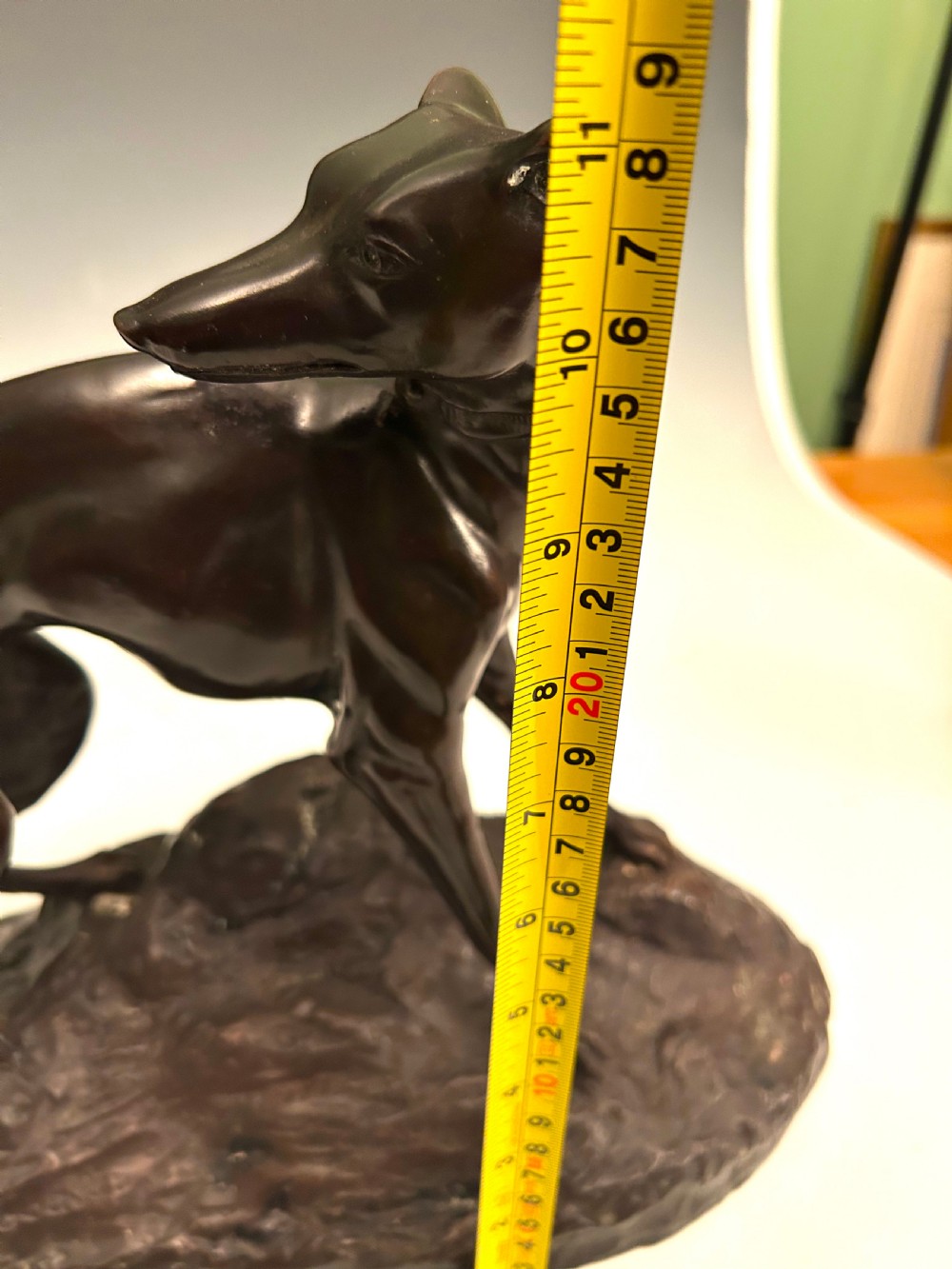 A dark brown patinated bronze sculpture depicting an alert standing greyhound on a textured naturalistic base. View VII